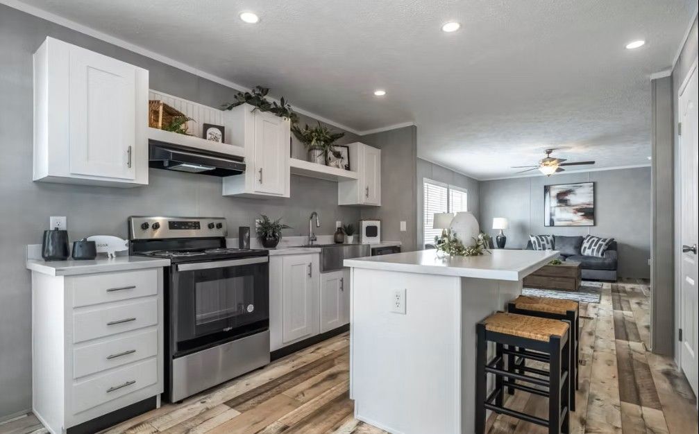 White kitchen with stainless steel appliances, breakfast bar, and open view to living room.