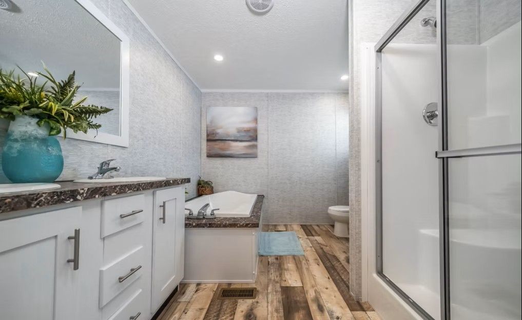Bathroom with white vanity, shower, tub, and wood-look flooring.