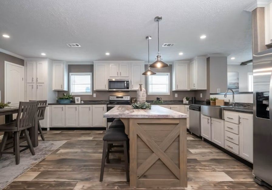 Kitchen with white cabinets, wood island, stainless steel appliances, and wood-look flooring.