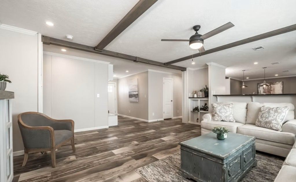Living room with wooden floors, neutral walls, and a light-colored sofa.