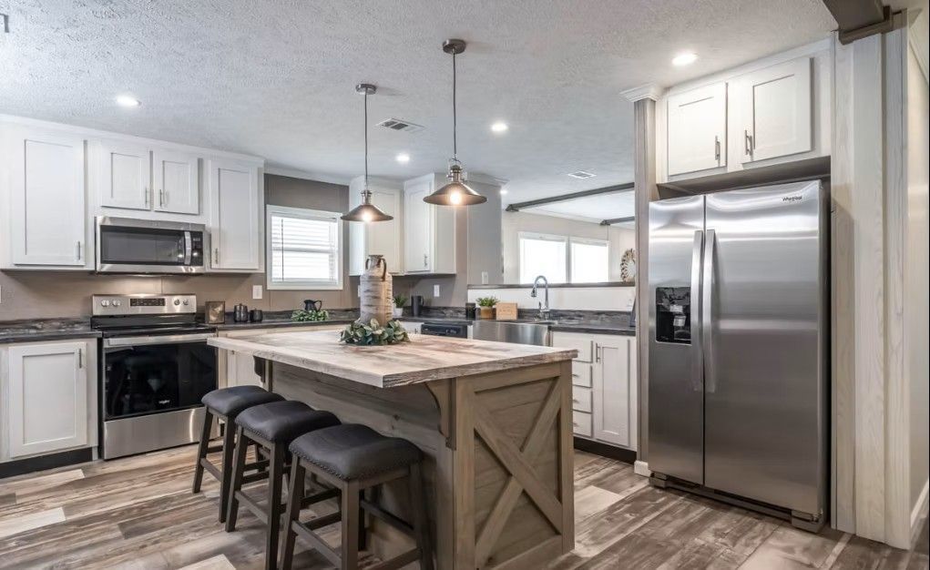 Modern kitchen with white cabinets, stainless steel appliances, and a gray island with stools.