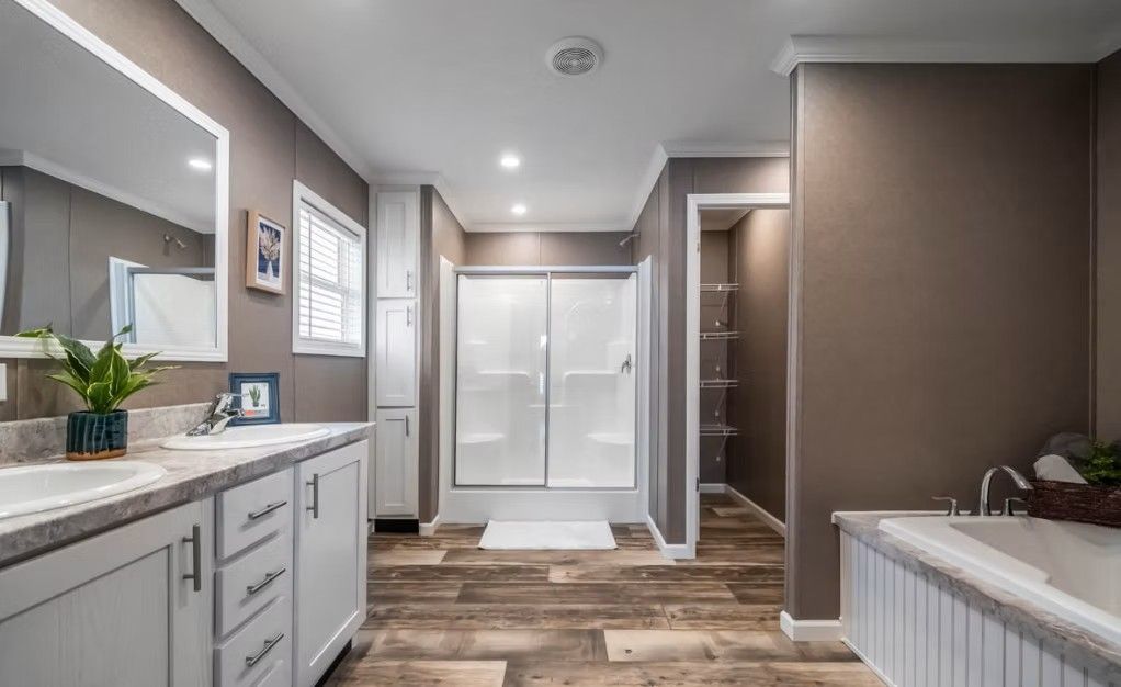 Bathroom with double sink vanity, shower, and soaking tub; neutral colors, wood-look flooring.