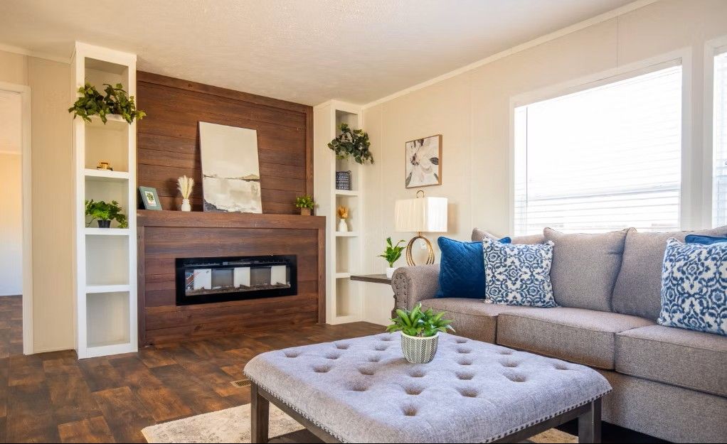 Living room with brown wood accent wall, built-in fireplace, shelving, and gray sofa with blue pillows.