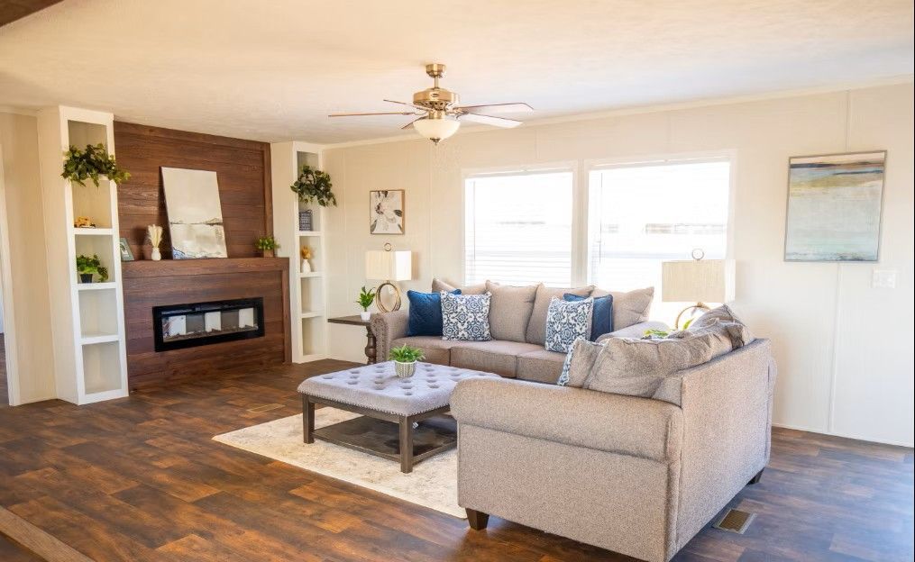 Living room with fireplace, couch, and windows. Brown floor, white walls.