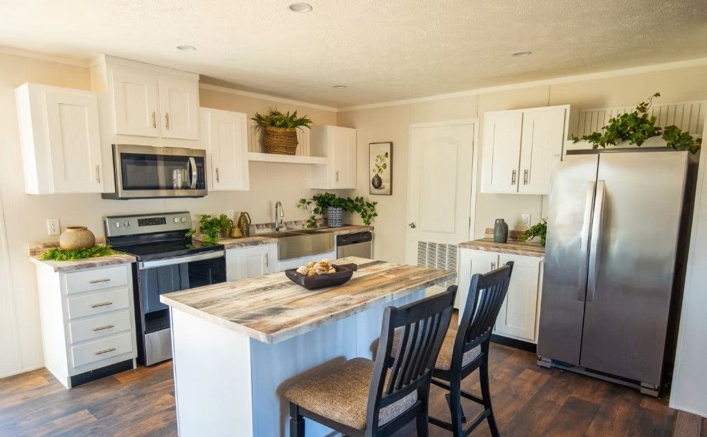 White kitchen with stainless steel appliances, a wooden island, and two black chairs.