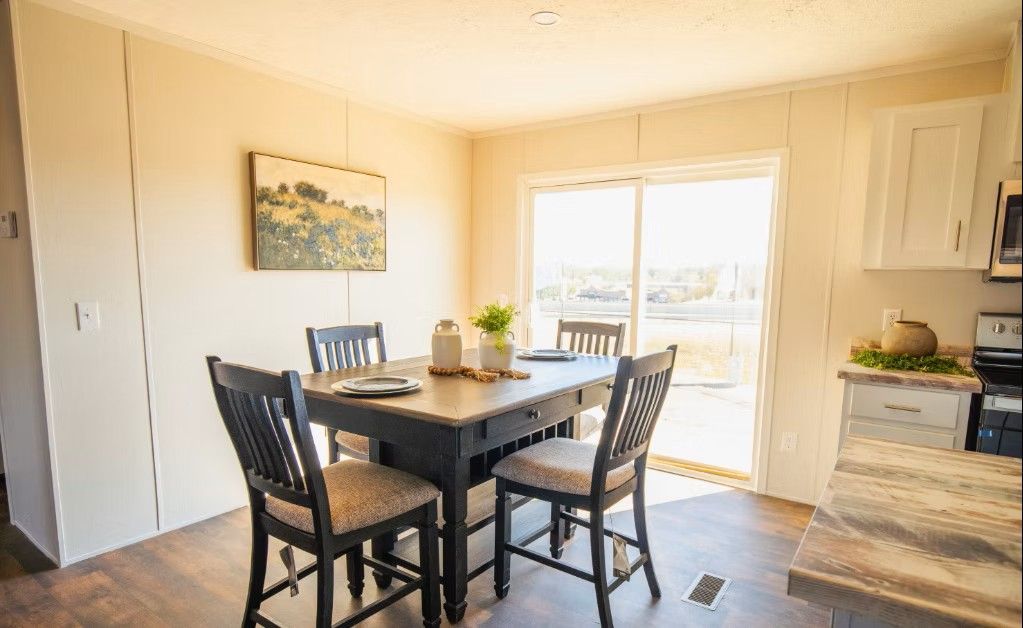 Dining area with table and chairs near sliding glass door, kitchen on right.