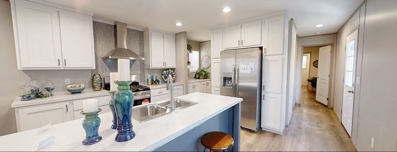 A modern kitchen with white cabinets, stainless steel appliances, and a blue island.