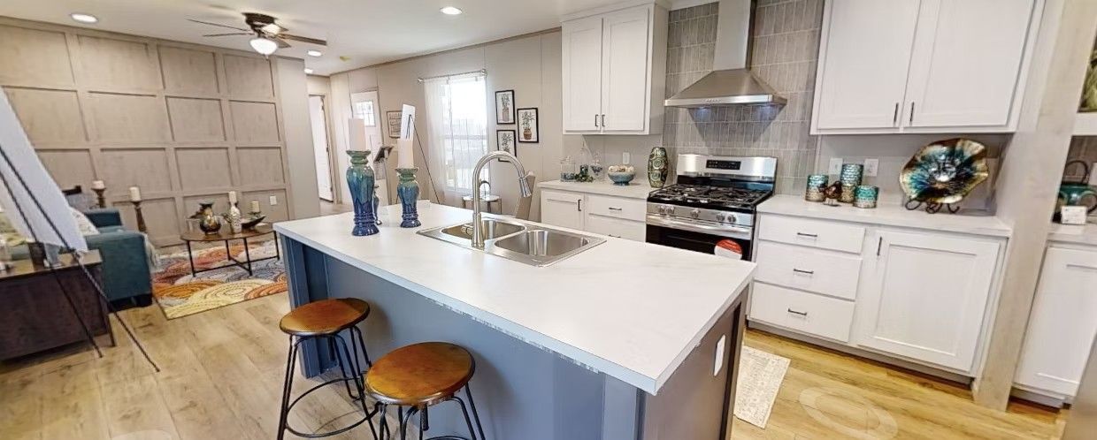 Kitchen with a gray island, white cabinets, and stainless steel appliances.