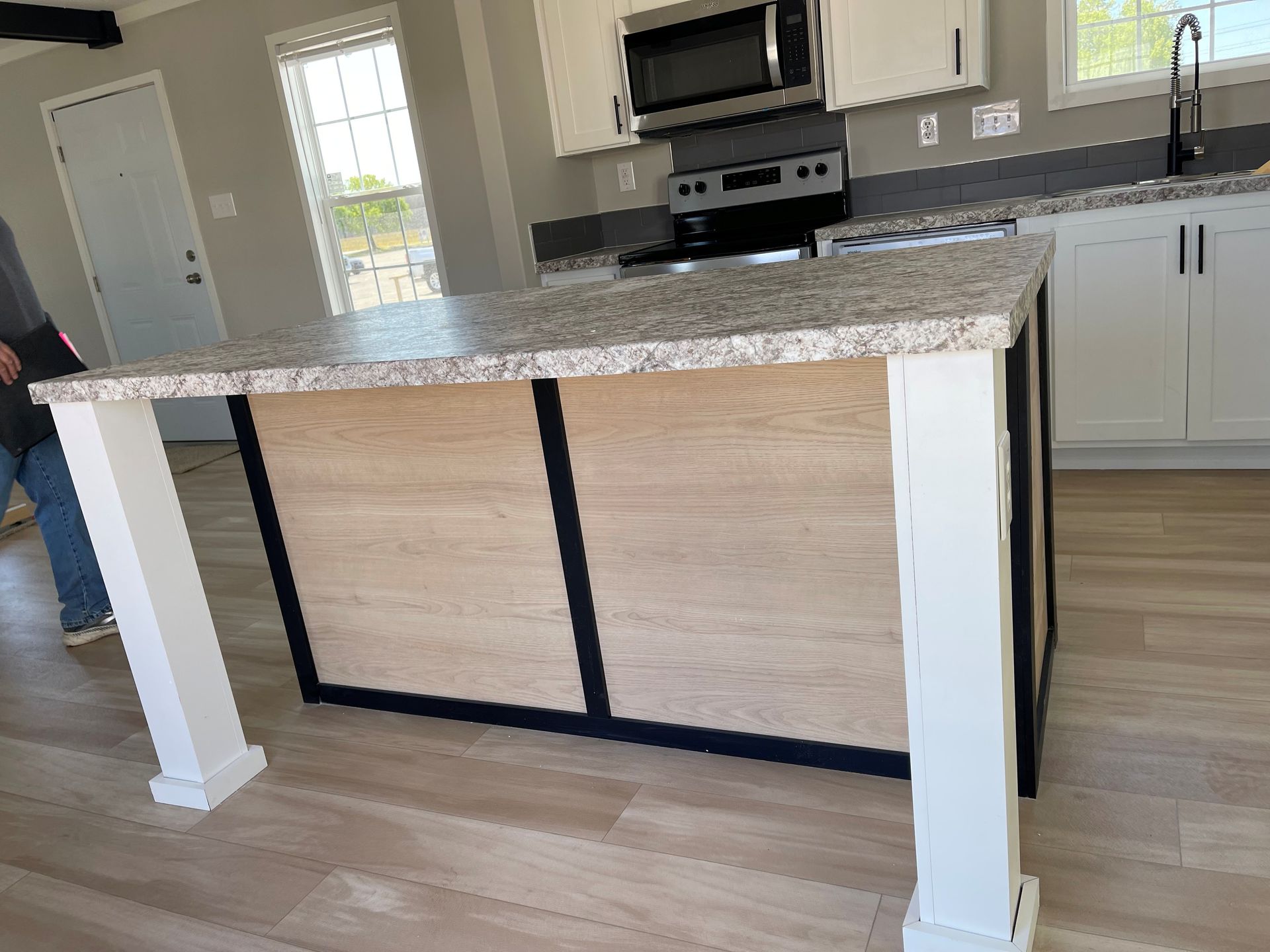 Kitchen island with speckled granite countertop and white supports in a bright modern kitchen