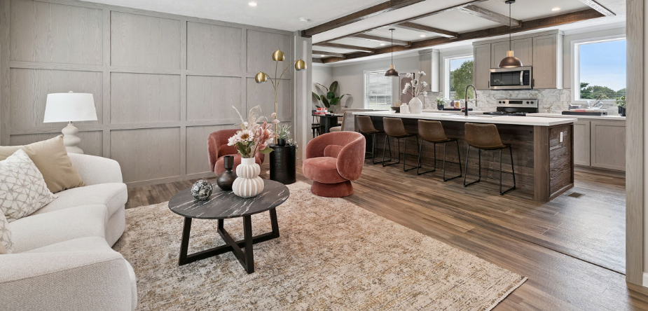 Elegant open-plan living room with beige sofa, pink chair, and kitchen island with stools.