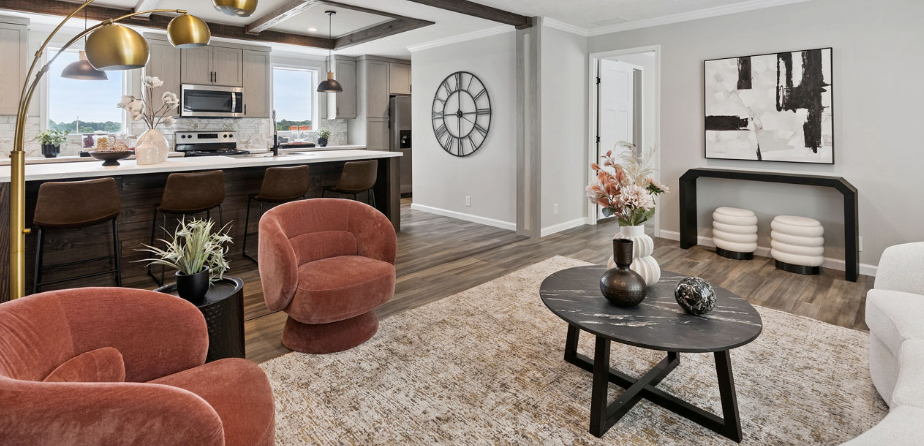 Cozy open-plan living room and kitchen with rust chairs, white sofa, black coffee table, and wall art