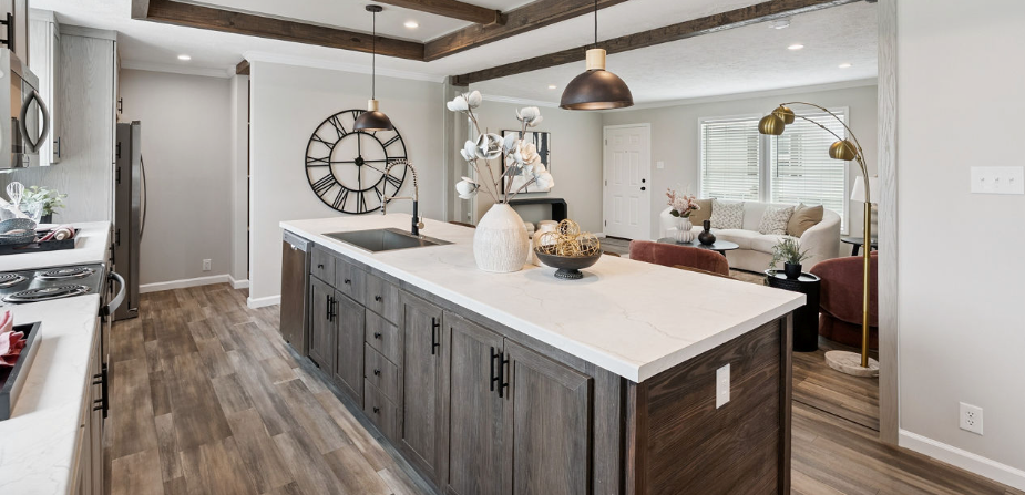 Bright modern kitchen with large island, white cabinets, wood floors, and wall clock in open dining area