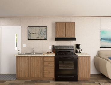 Modern kitchen with light wood cabinets, black stove, coffee maker, framed art, and beige sofa nearby