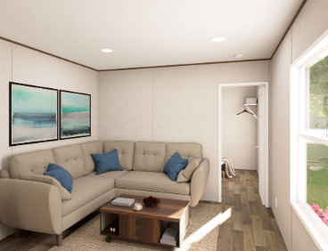 Small beige living room with sectional sofa, blue pillows, coffee table, wall art, and a window seat.