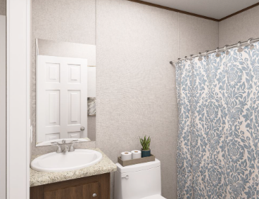 Small bathroom with white sink, toilet, and blue patterned shower curtain.