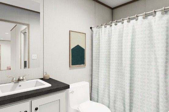 Bright bathroom with white shower curtain, white vanity, and black countertop mirror.
