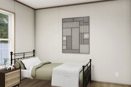 Spartan bedroom with twin iron beds, white walls, window light, and a framed gray wall hanging
