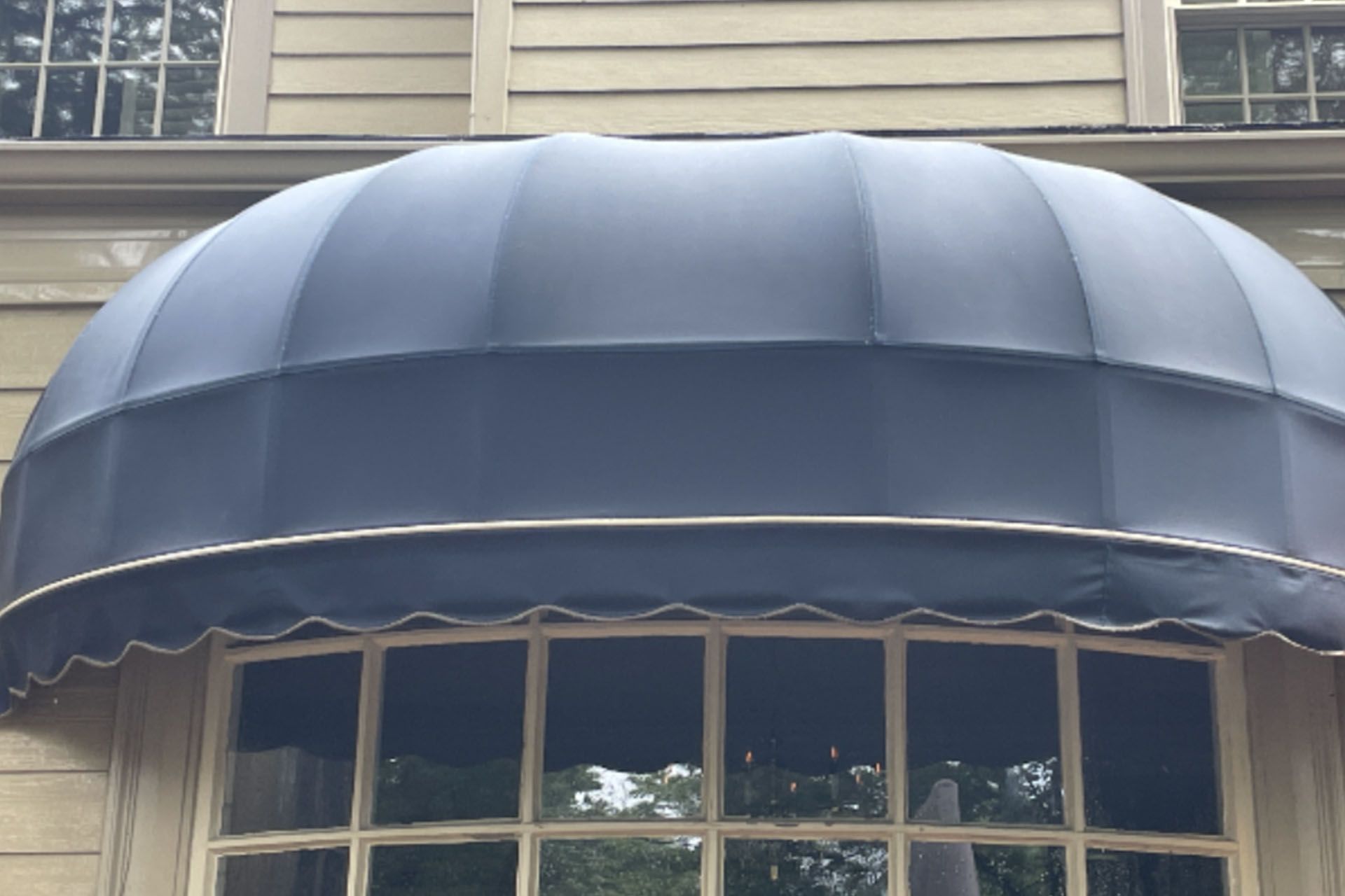 Dark blue awning over a row of windows on a beige house