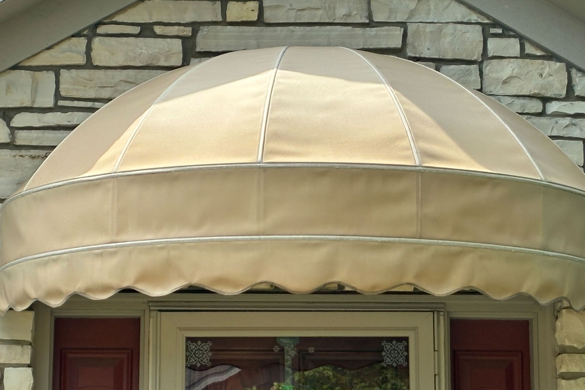 Beige striped awning over a window on a stone exterior wall