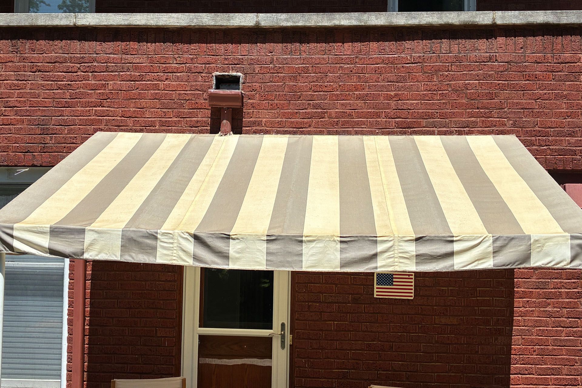 Striped beige awning extending from a brick building facade