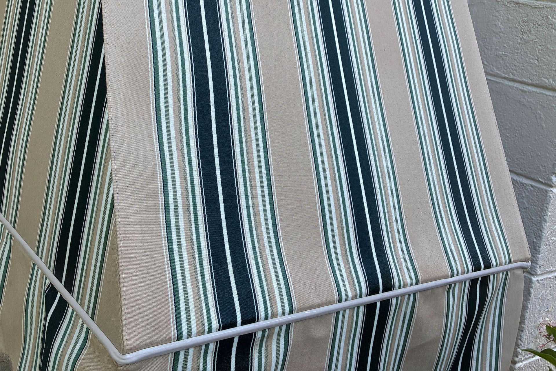 Striped outdoor chair cushion with teal, beige, and gray bands on a patio chair