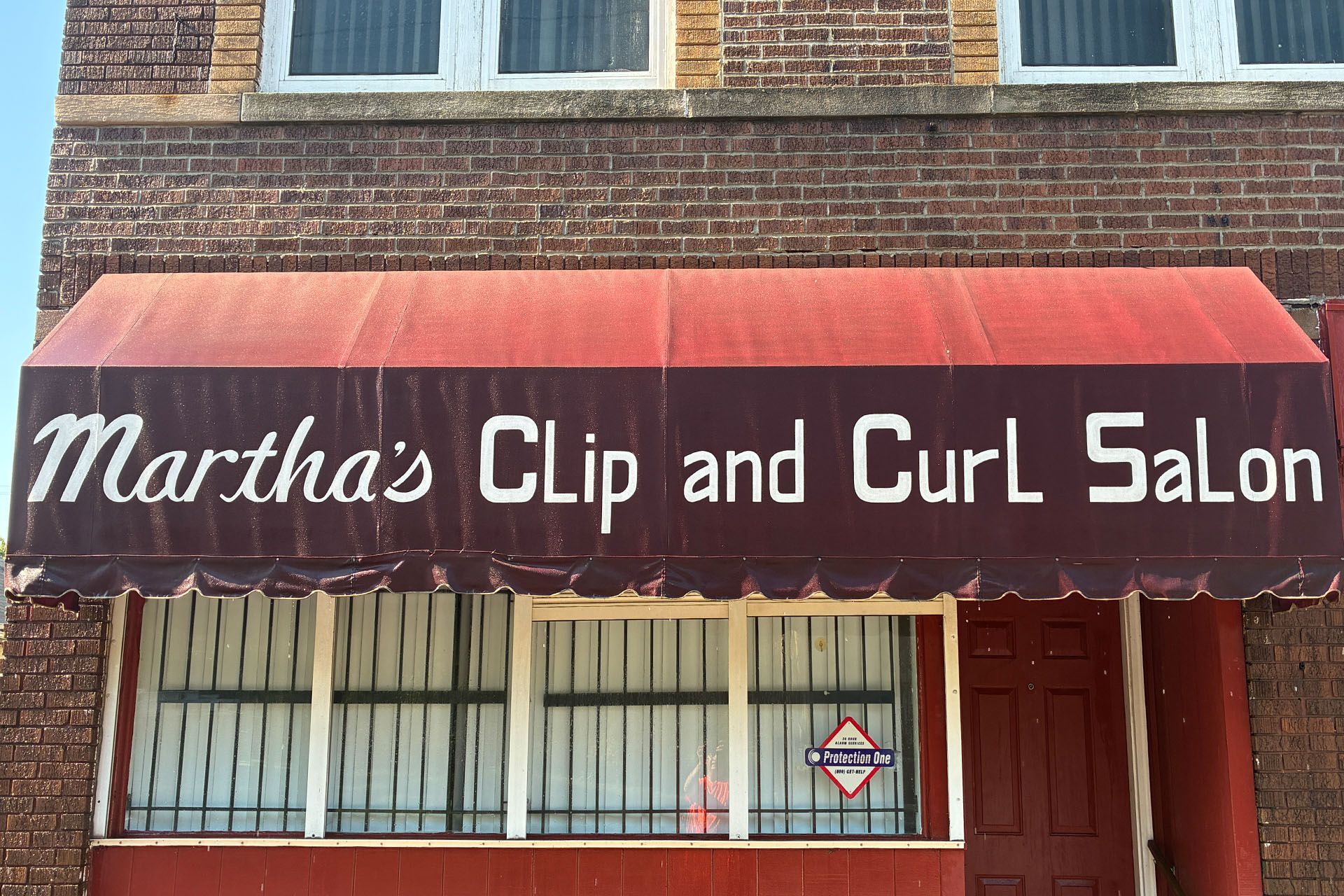 Martha’s Clip and Curl Salon storefront with maroon awning and brick facade