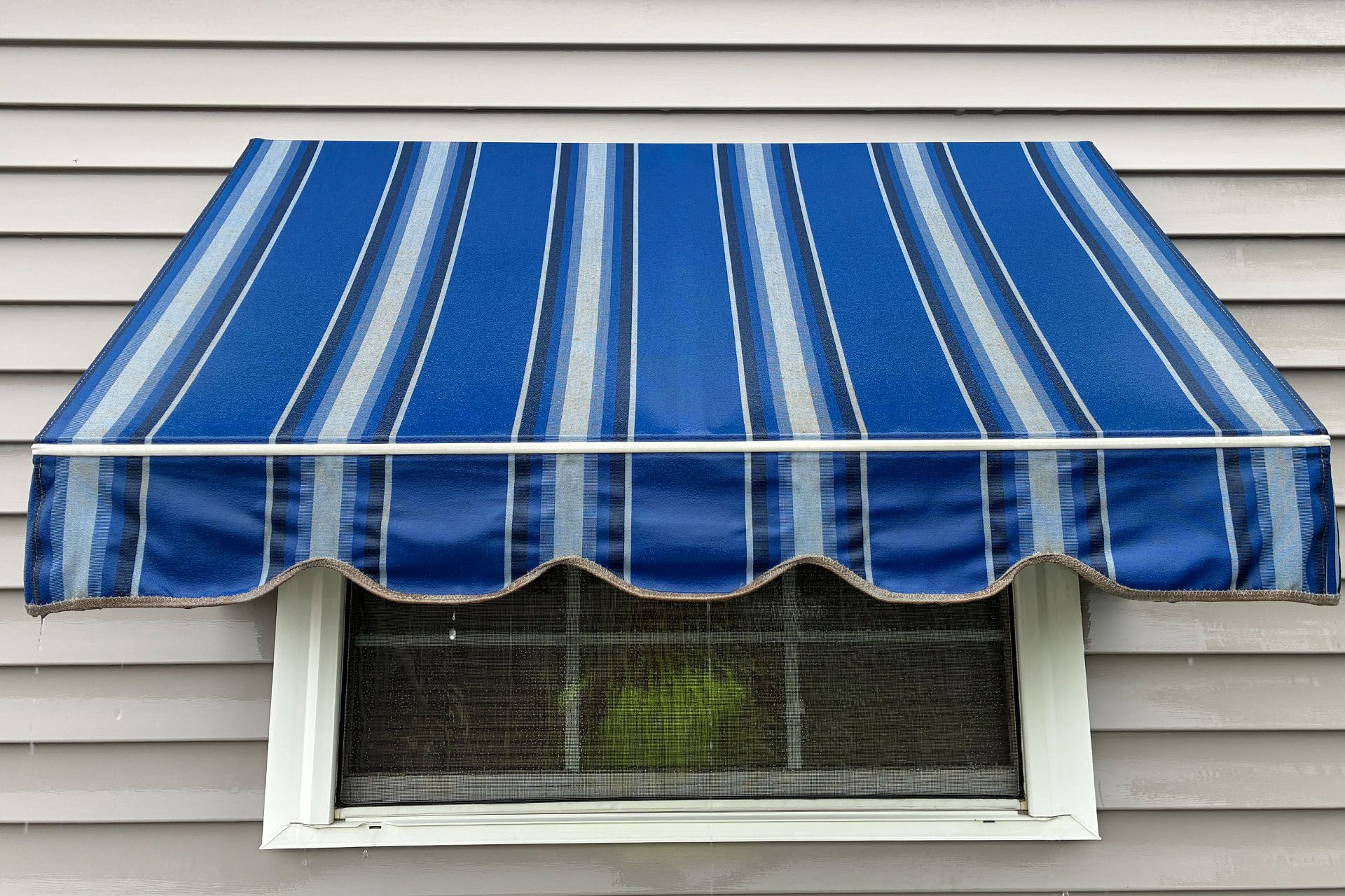 Blue-and-white striped awning over a window on a house exterior