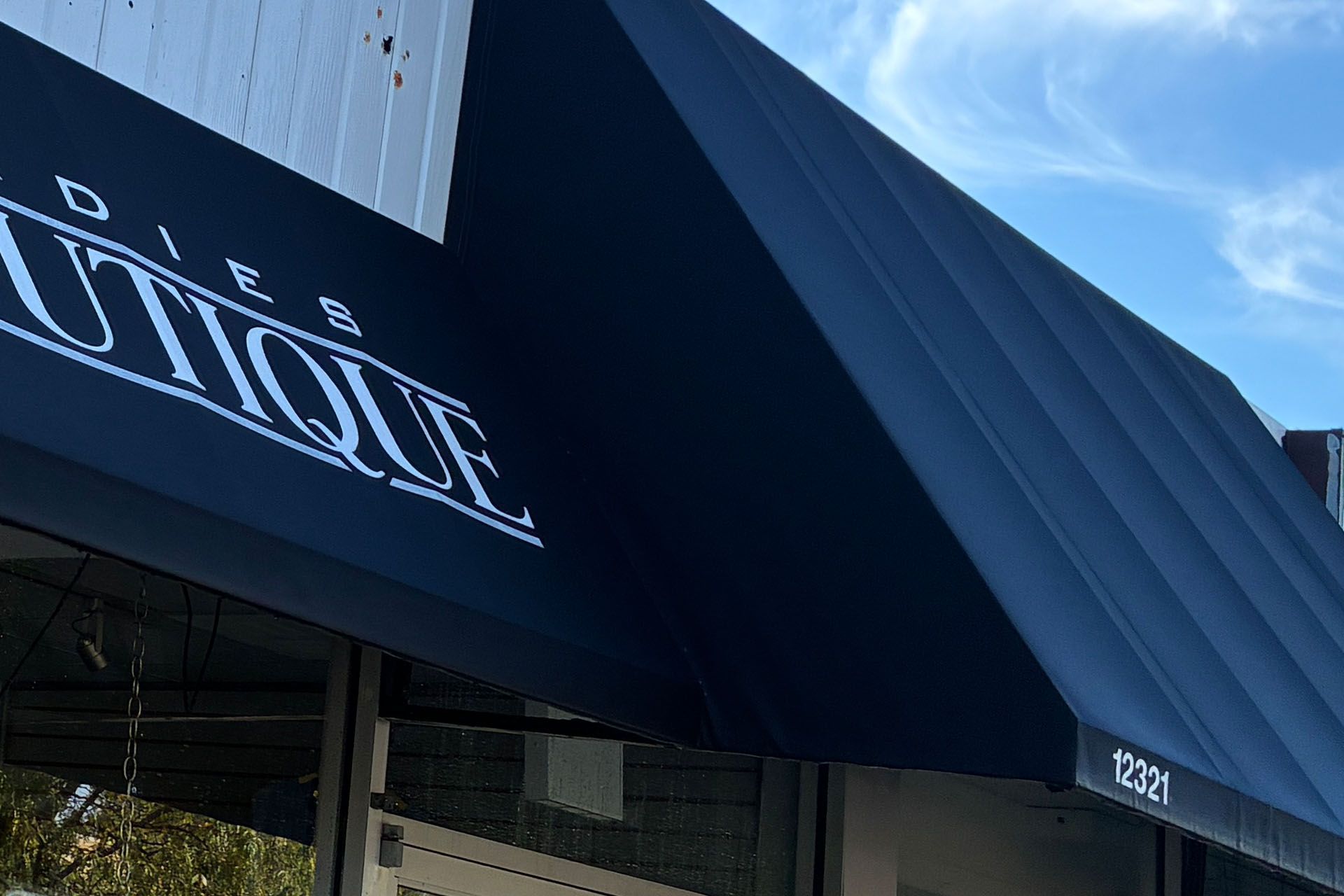 Black awning with white logo on a modern building under a blue sky