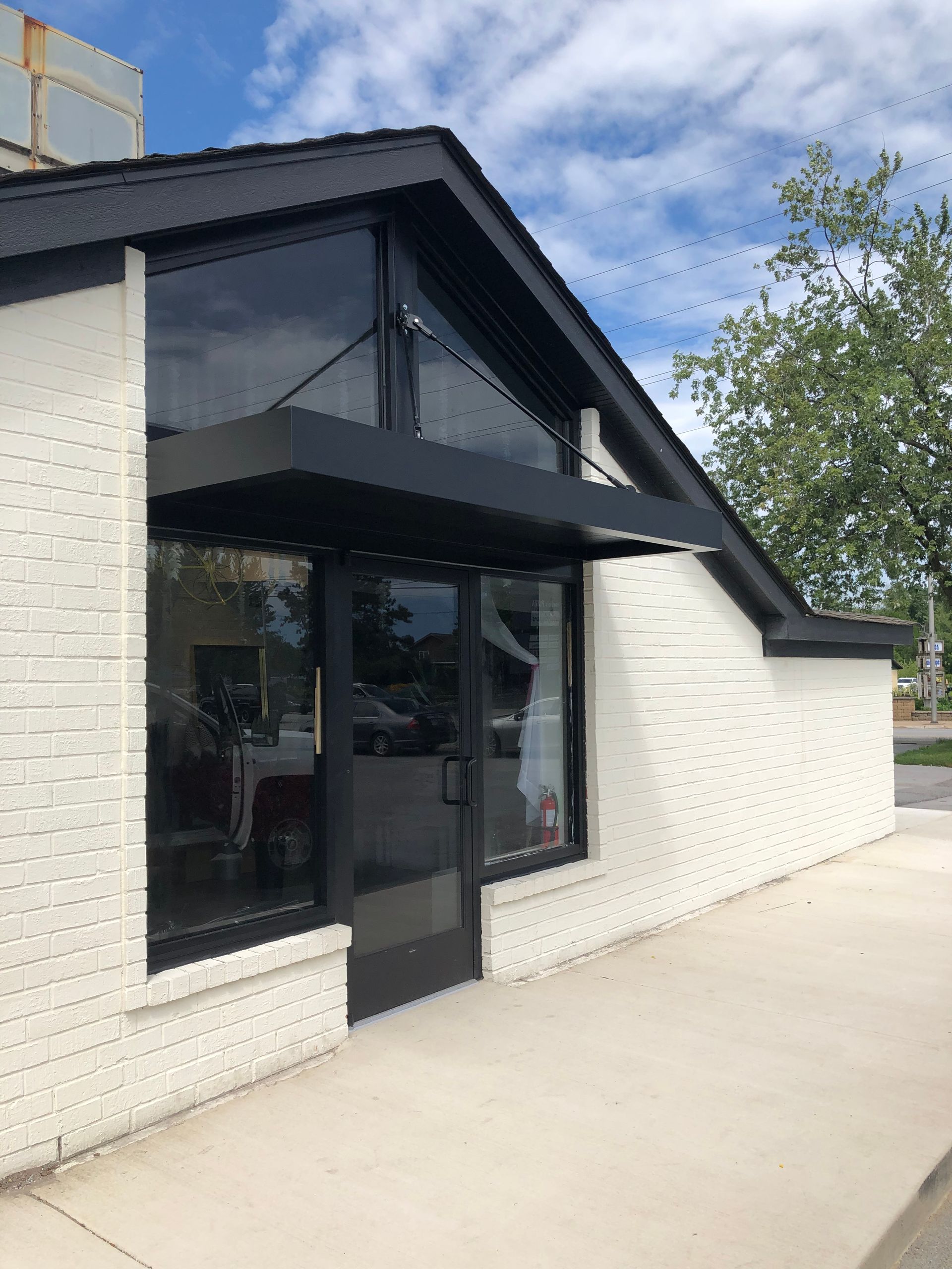 Modern storefront with black awning, large glass windows, and white brick exterior
