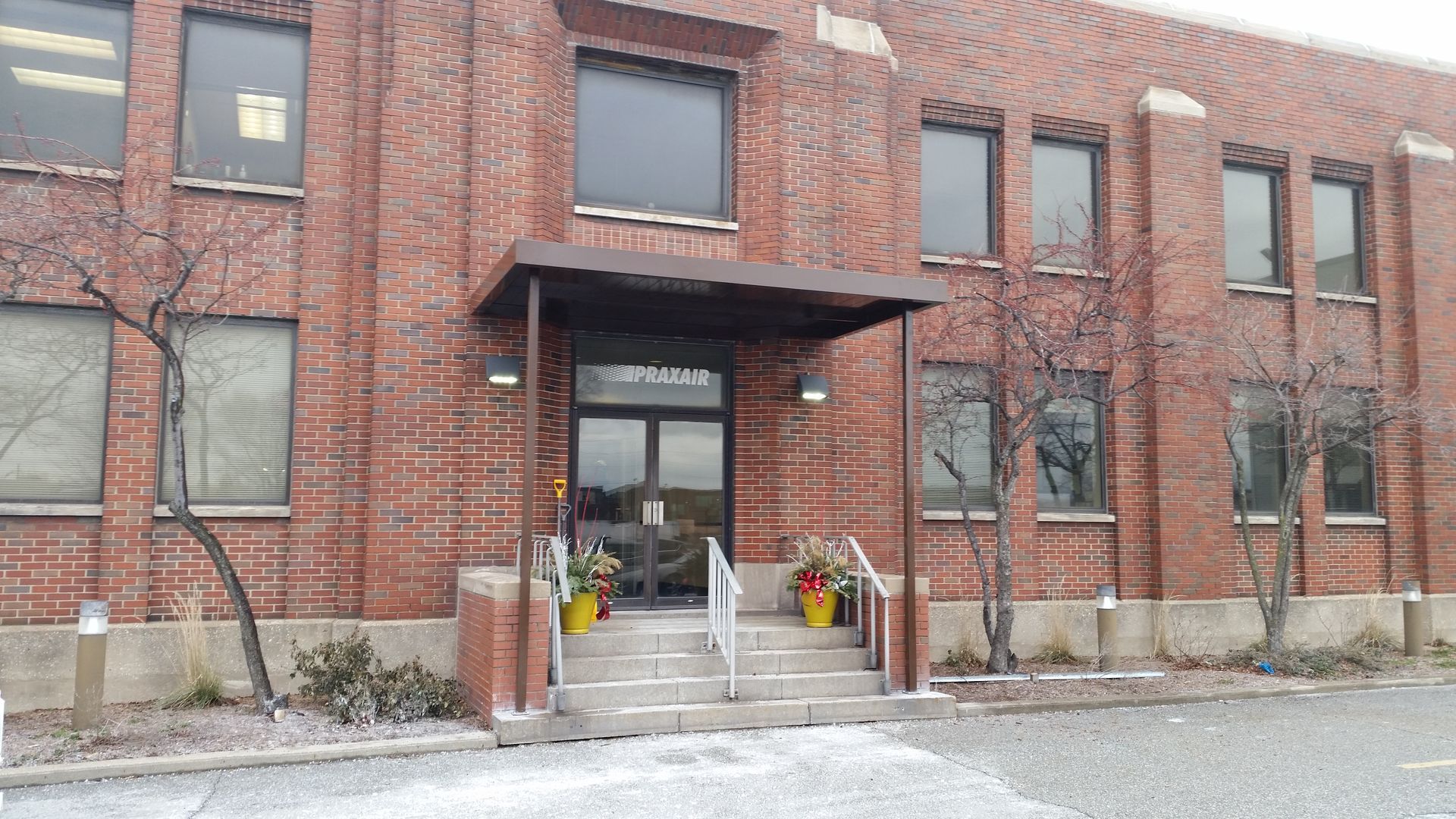 Brick office building entrance with steps, awning, and snow on the ground