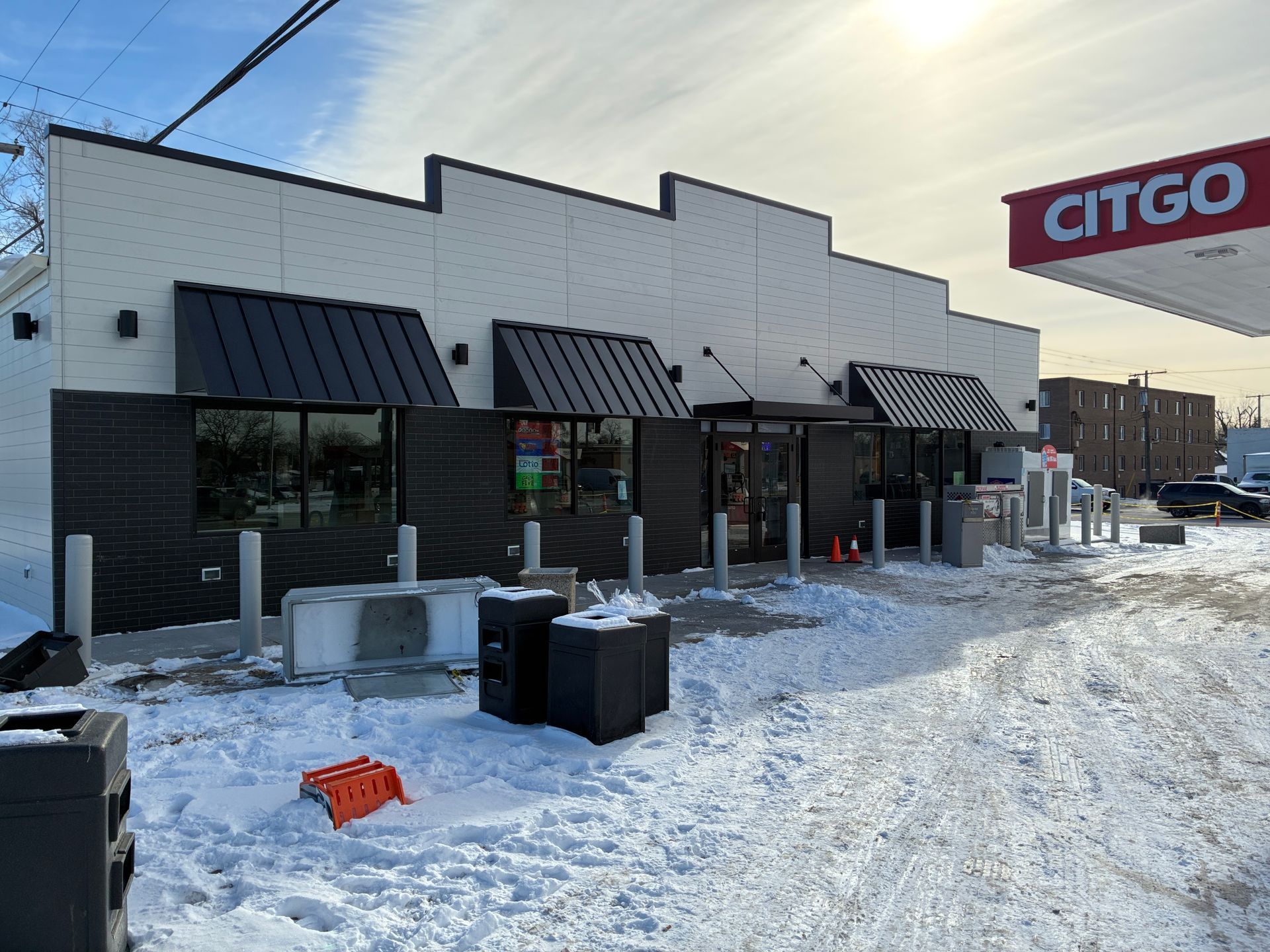 Snow-covered Citgo convenience store with black awnings and a trash can outside