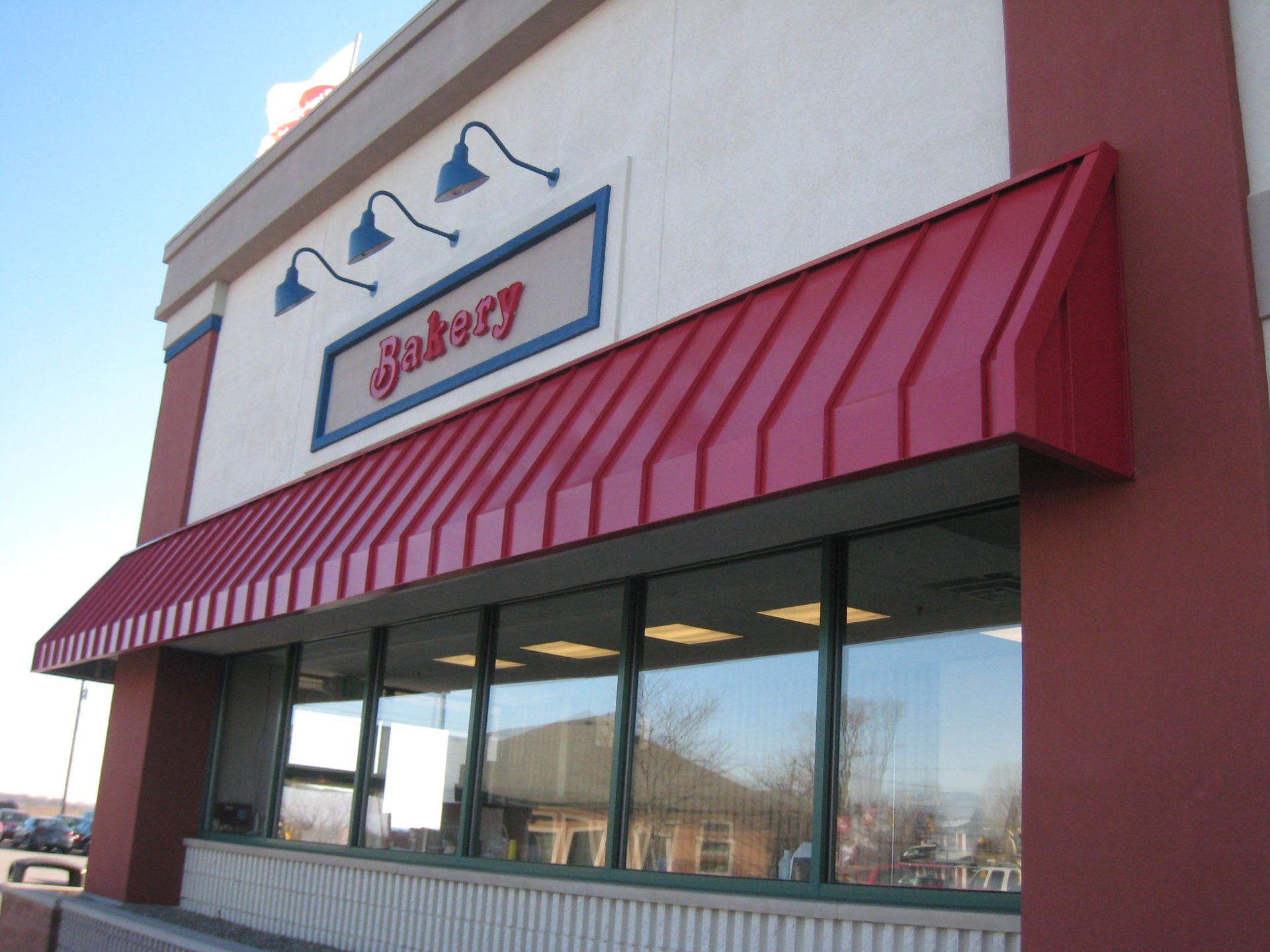 Storefront with red awning and large windows on a sunny day