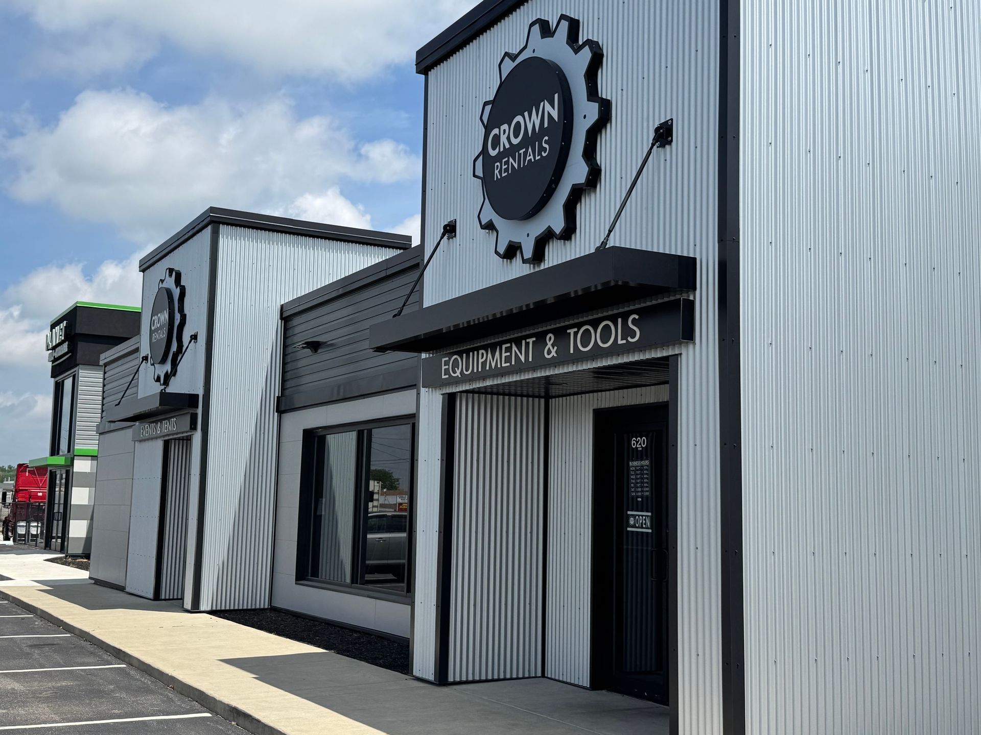 Storefronts for a western and tools shop on a city street, with black-and-white signage and metal siding.