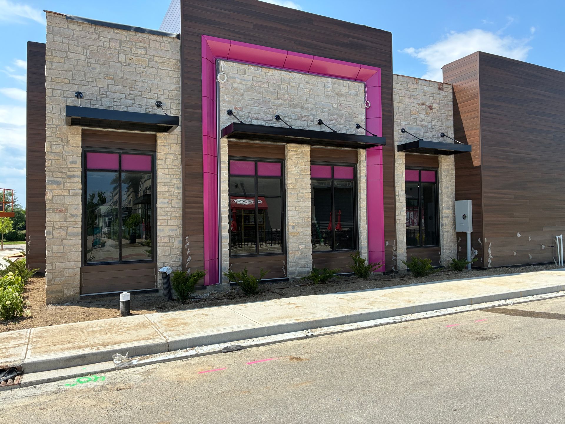 Storefront with pink trim and large glass windows on a quiet street.