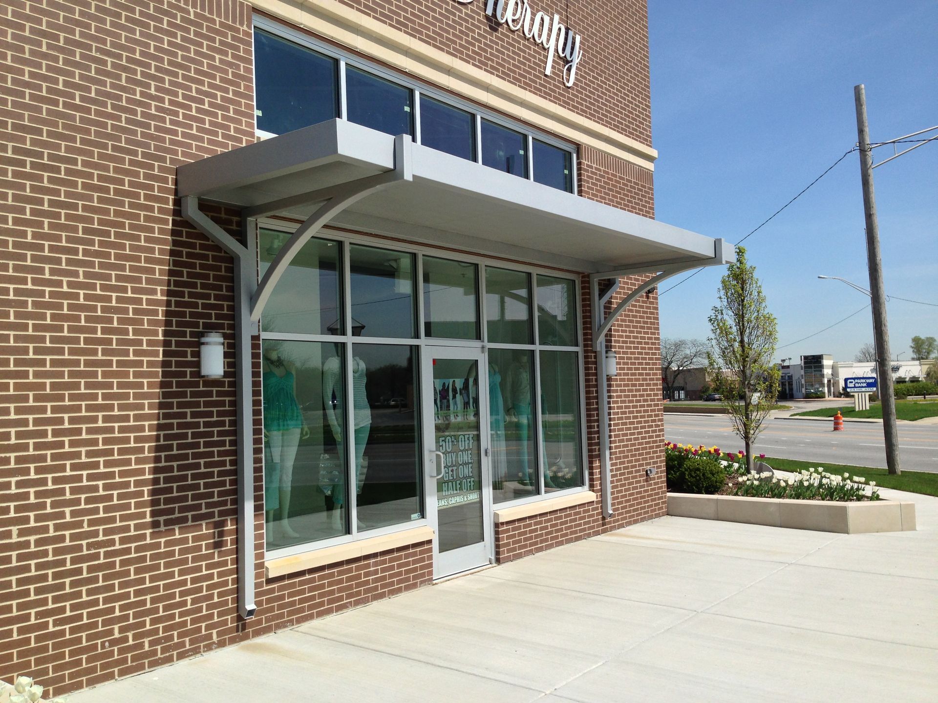 Brick storefront entrance with glass doors and a gray awning beside a sidewalk