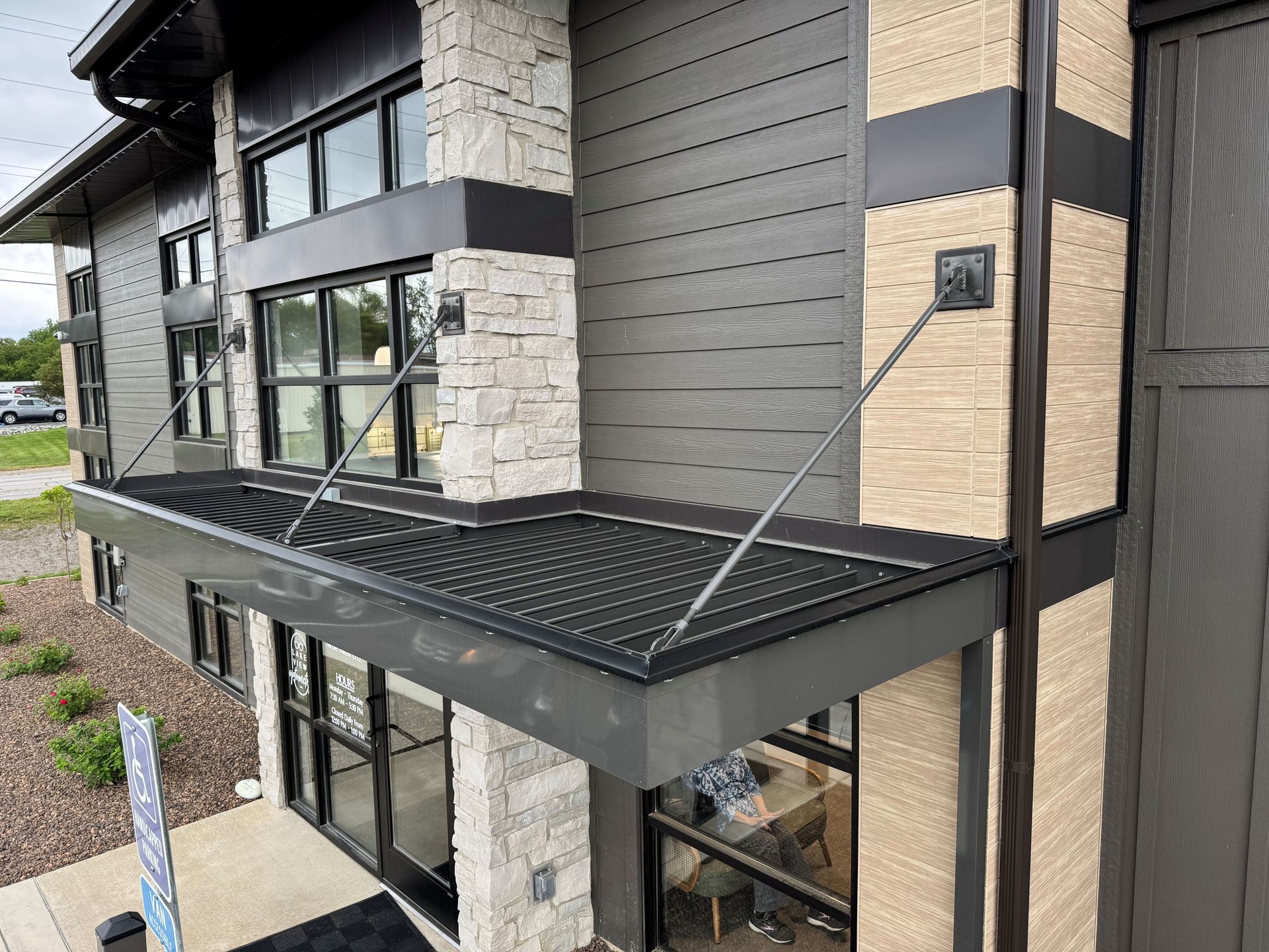 Modern building exterior with black awning, stone accents, and large windows