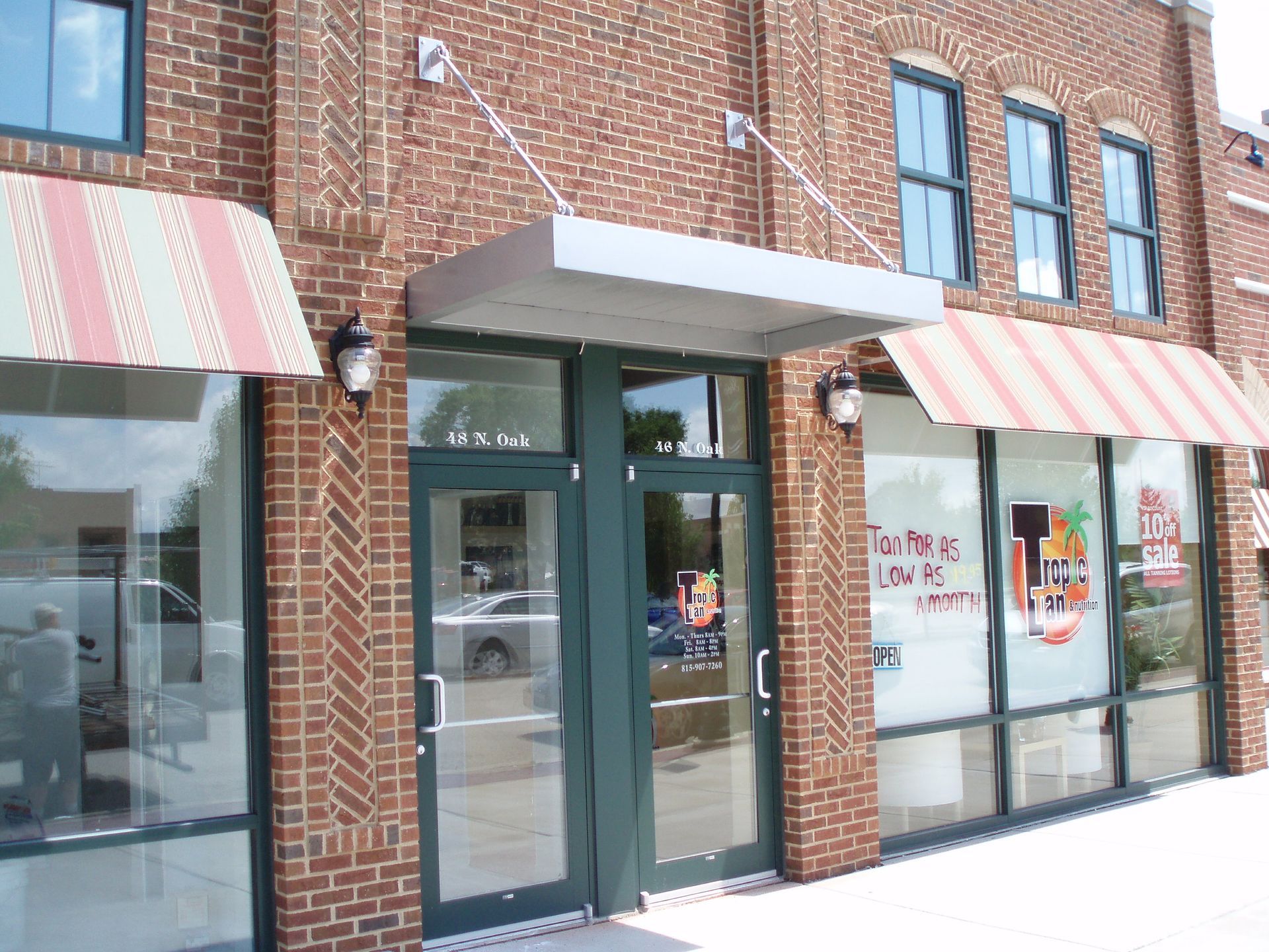 Brick storefront with striped awnings and glass doors in a snowy streetscape