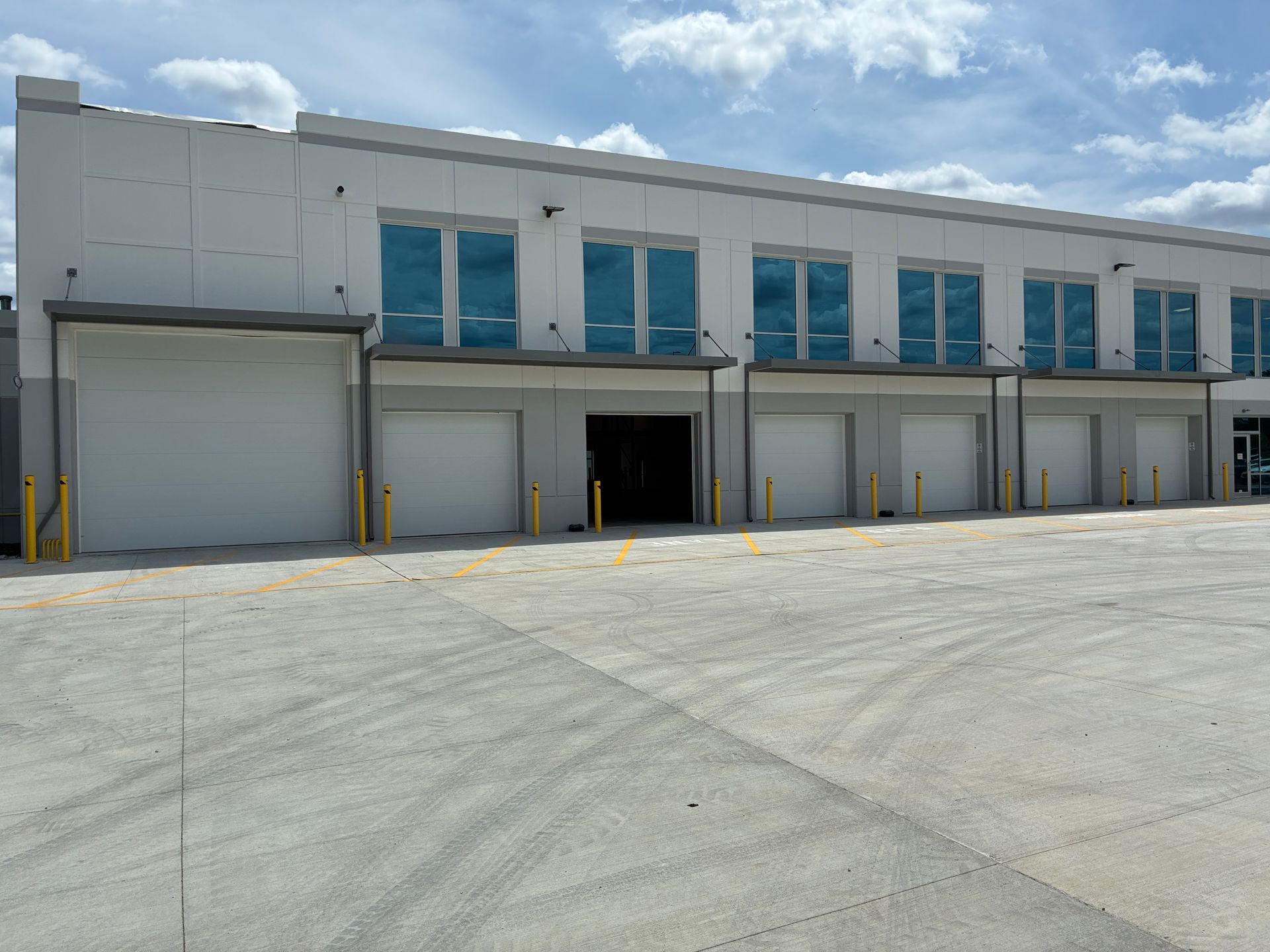 Industrial warehouse with multiple loading docks and a large roll-up door under a blue sky