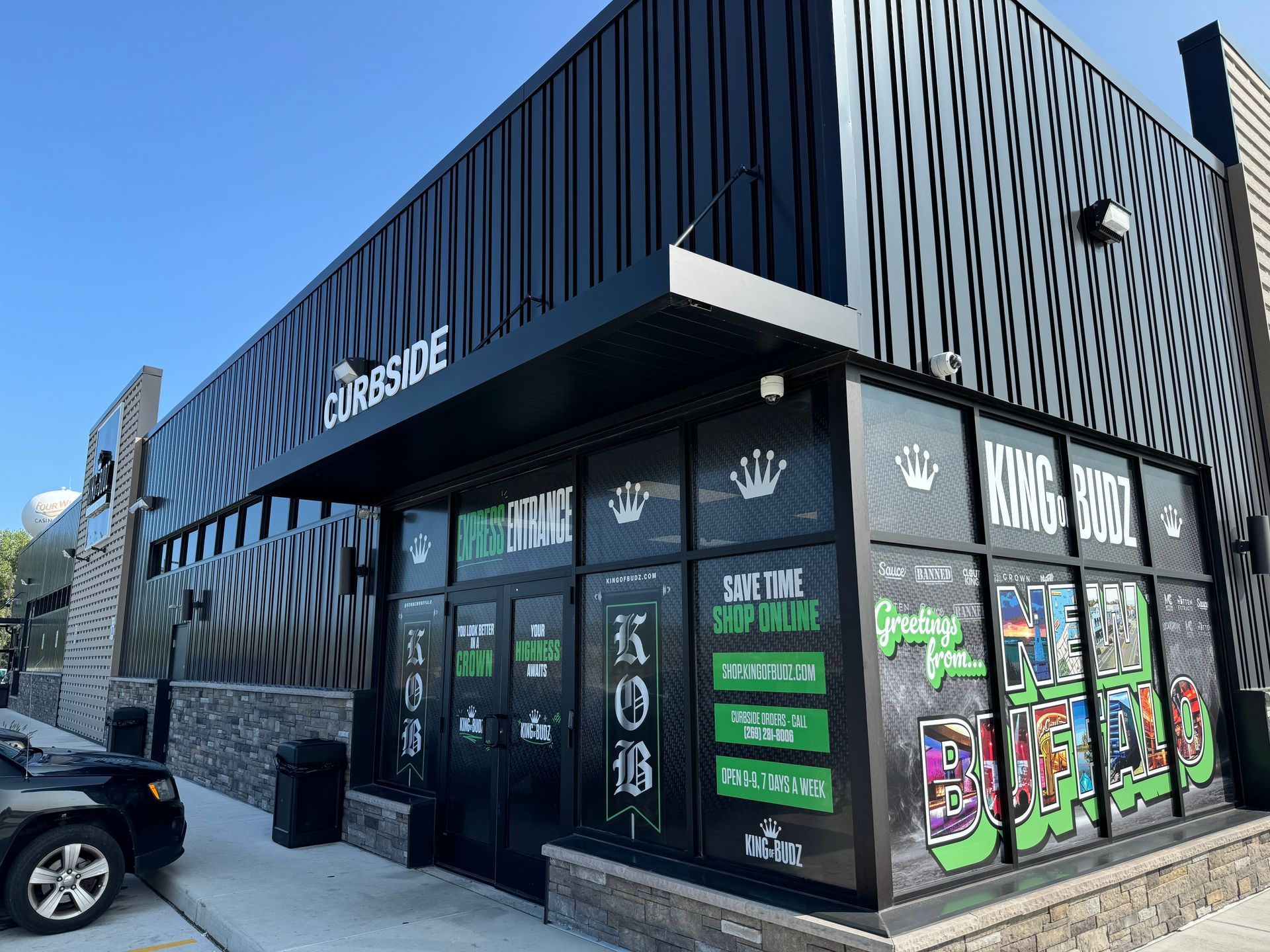 Black modern storefront with glass windows and bold signage in a parking lot