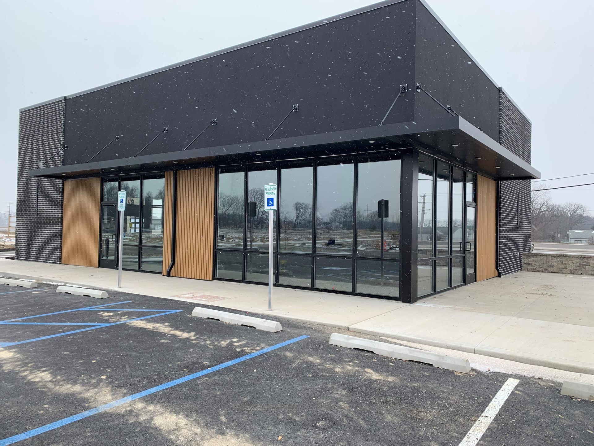 Modern storefront with black facade, glass windows, and accessible parking in front