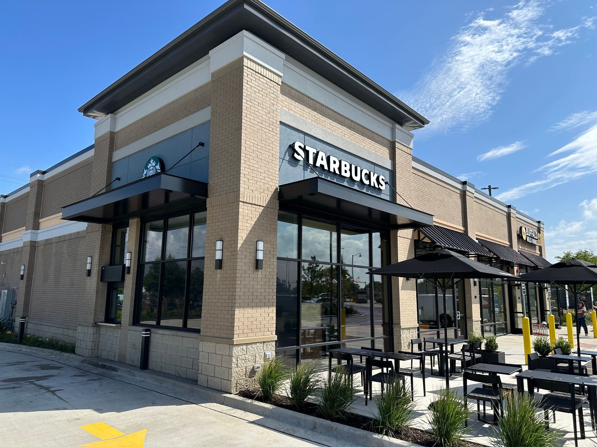 Starbucks storefront with outdoor patio seating on a sunny day
