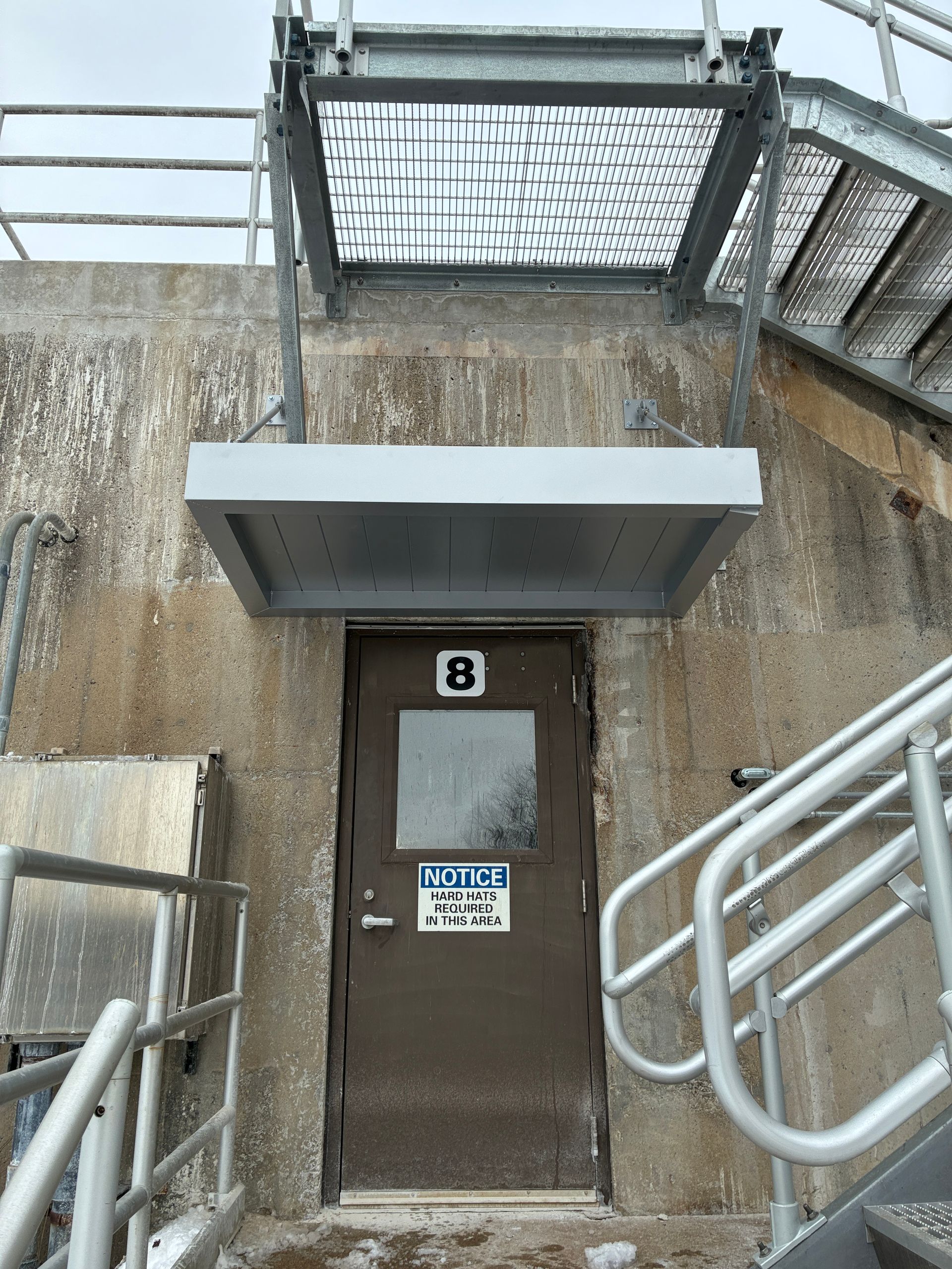 Outdoor concrete stair landing with a metal door marked 8 and a blue “ACTIVE” sign.