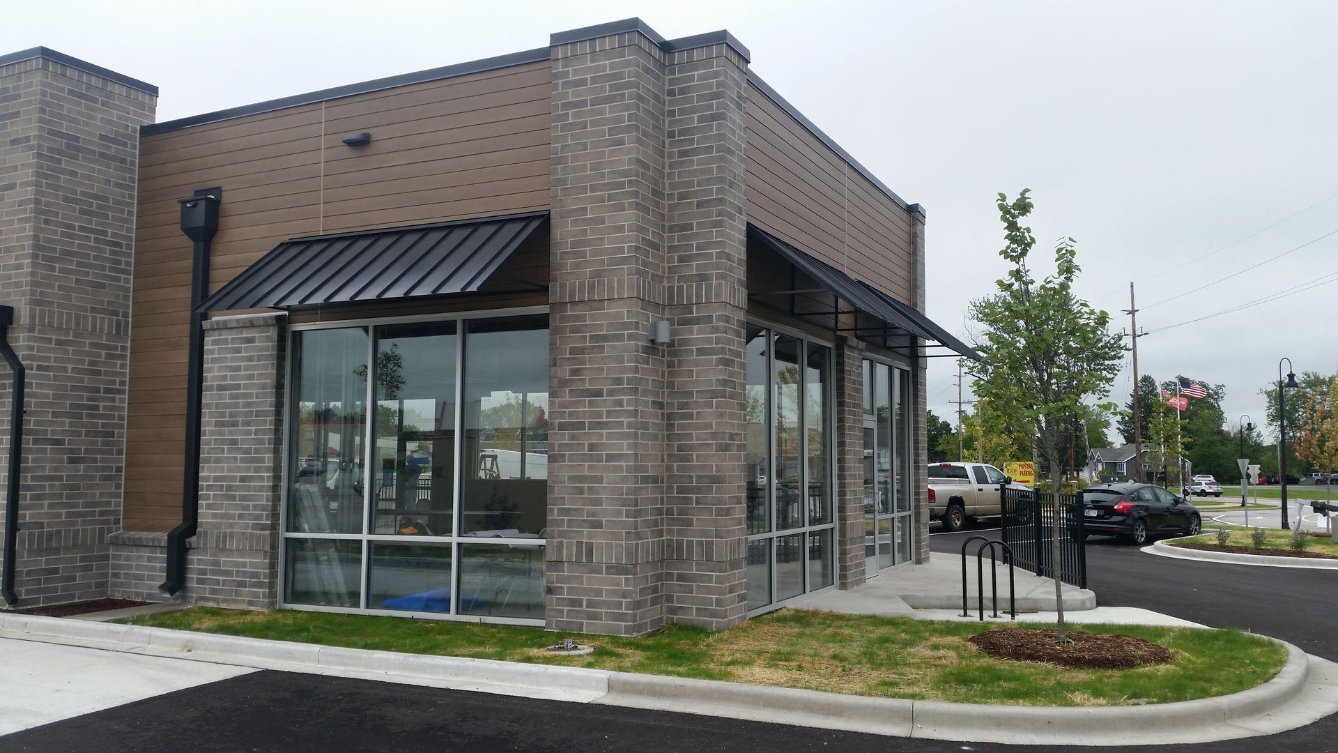 Corner brick storefront with large glass windows and a small landscaped curb