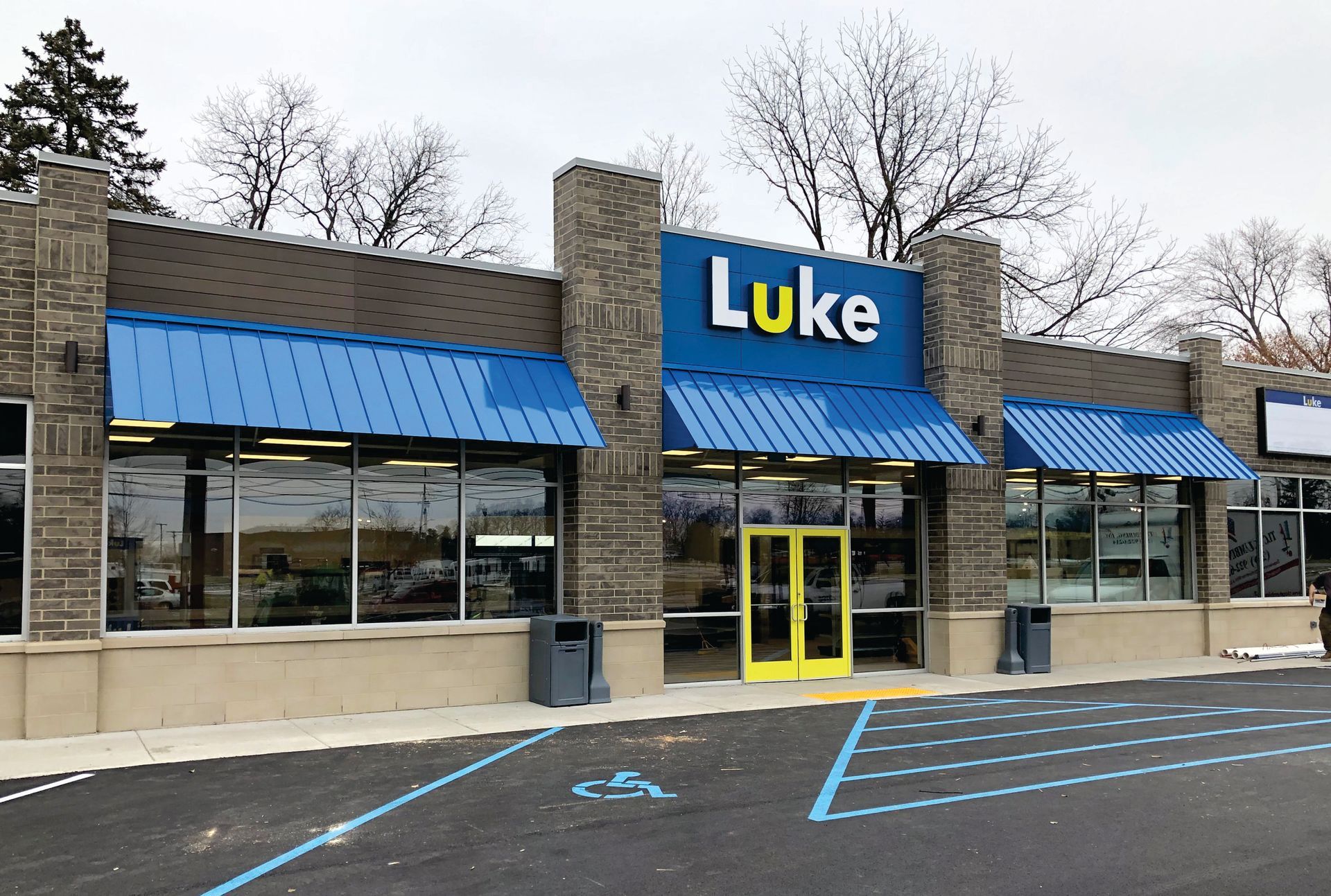Luke store exterior with blue awnings and yellow doors in a parking lot
