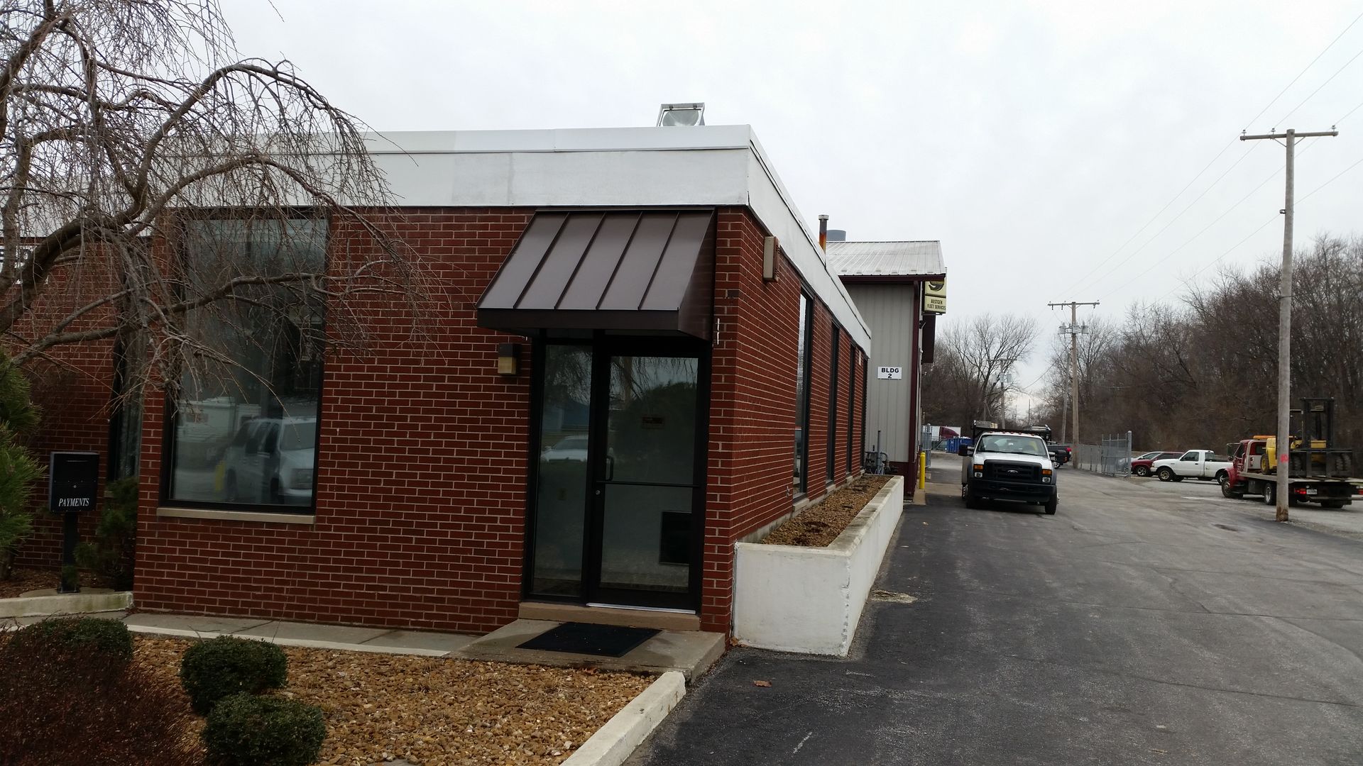 Brick building corner with glass door and windows beside an empty street on a cloudy day