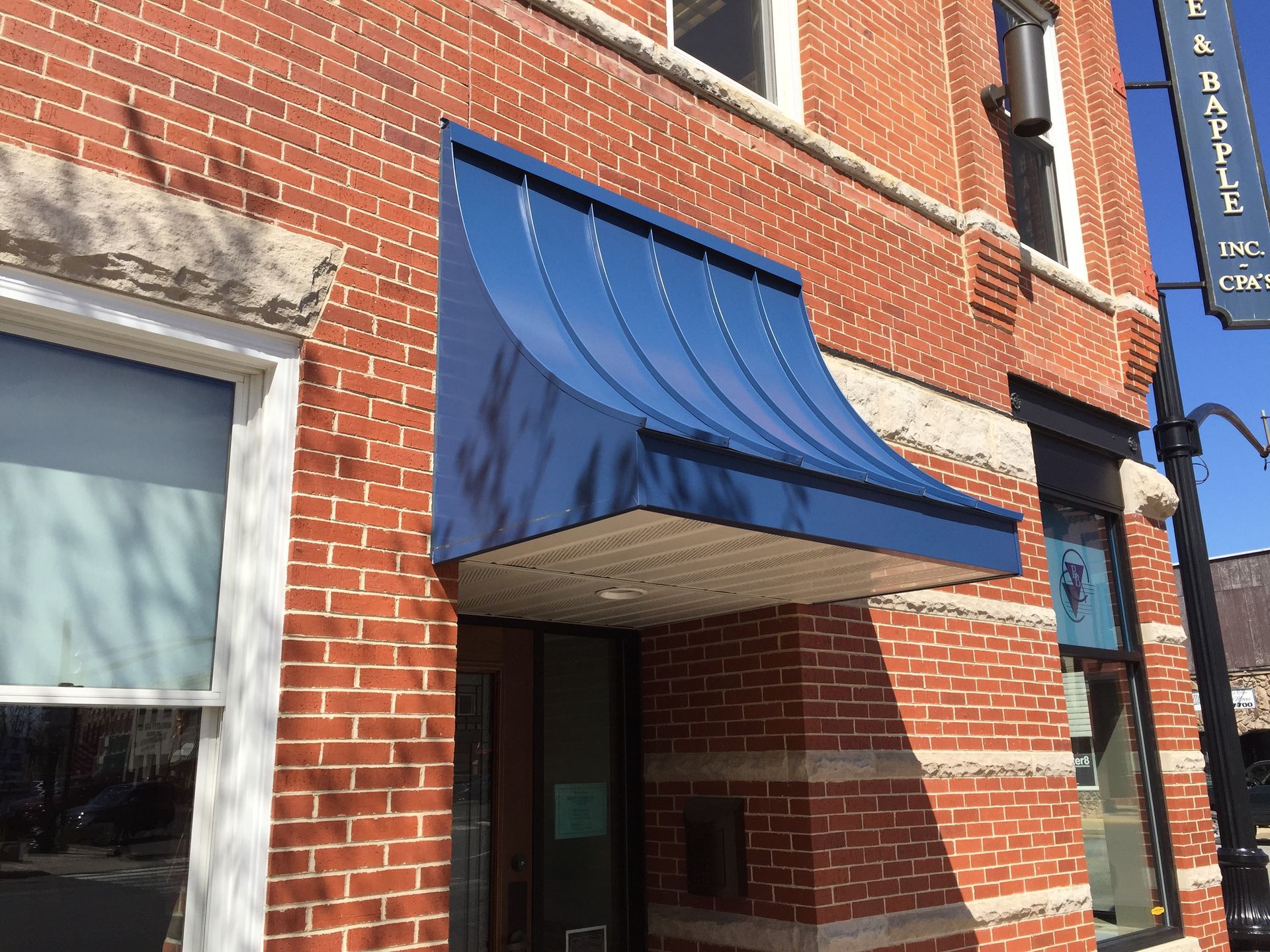 Blue awning over a brick storefront entrance on a city street