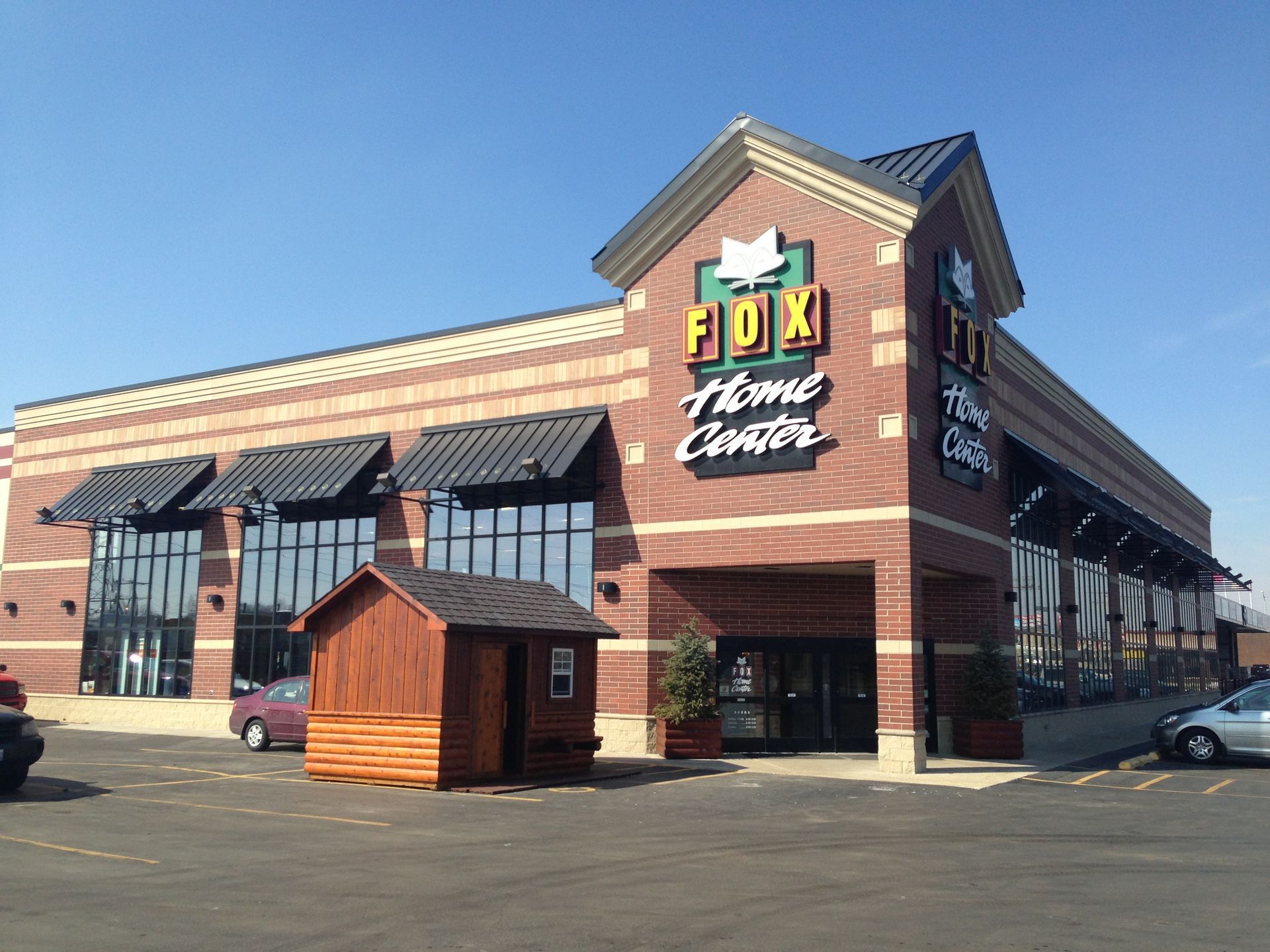Exterior of Fox Town Center brick building with striped awnings and a small wooden shed in front