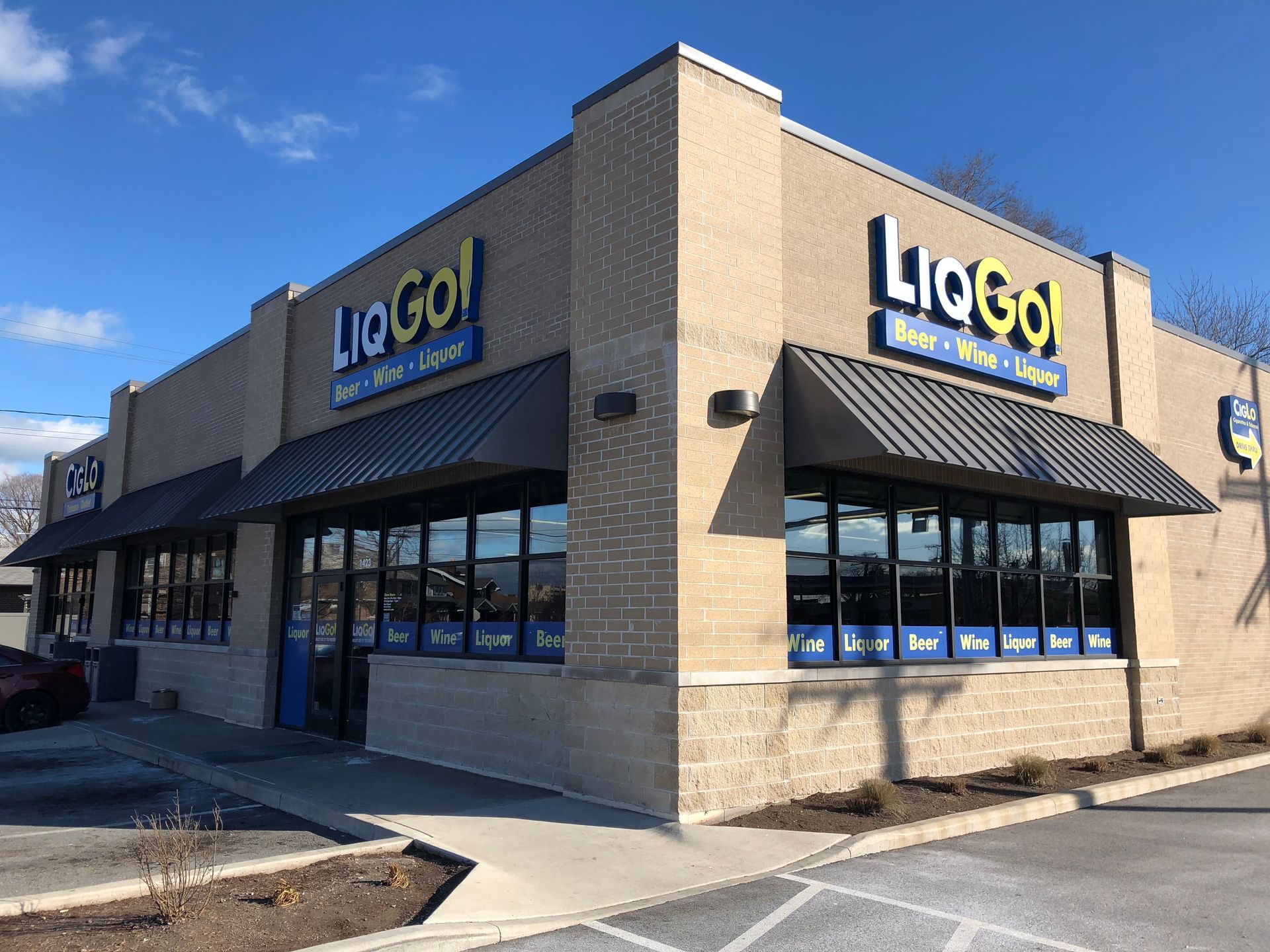 LiGo supermarket storefront with black awnings and large windows on a sunny corner lot