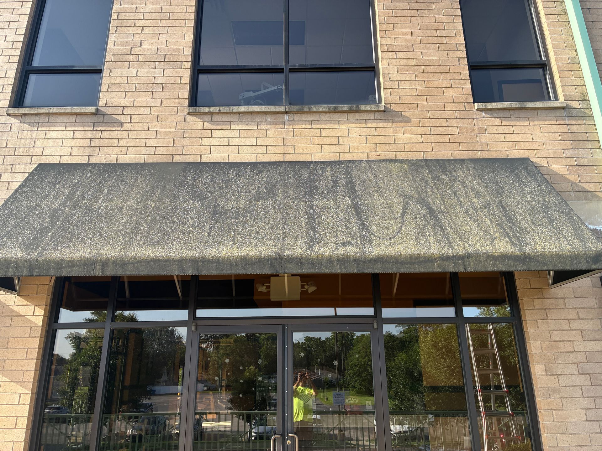 Brick storefront with a dark awning and glass entrance doors.