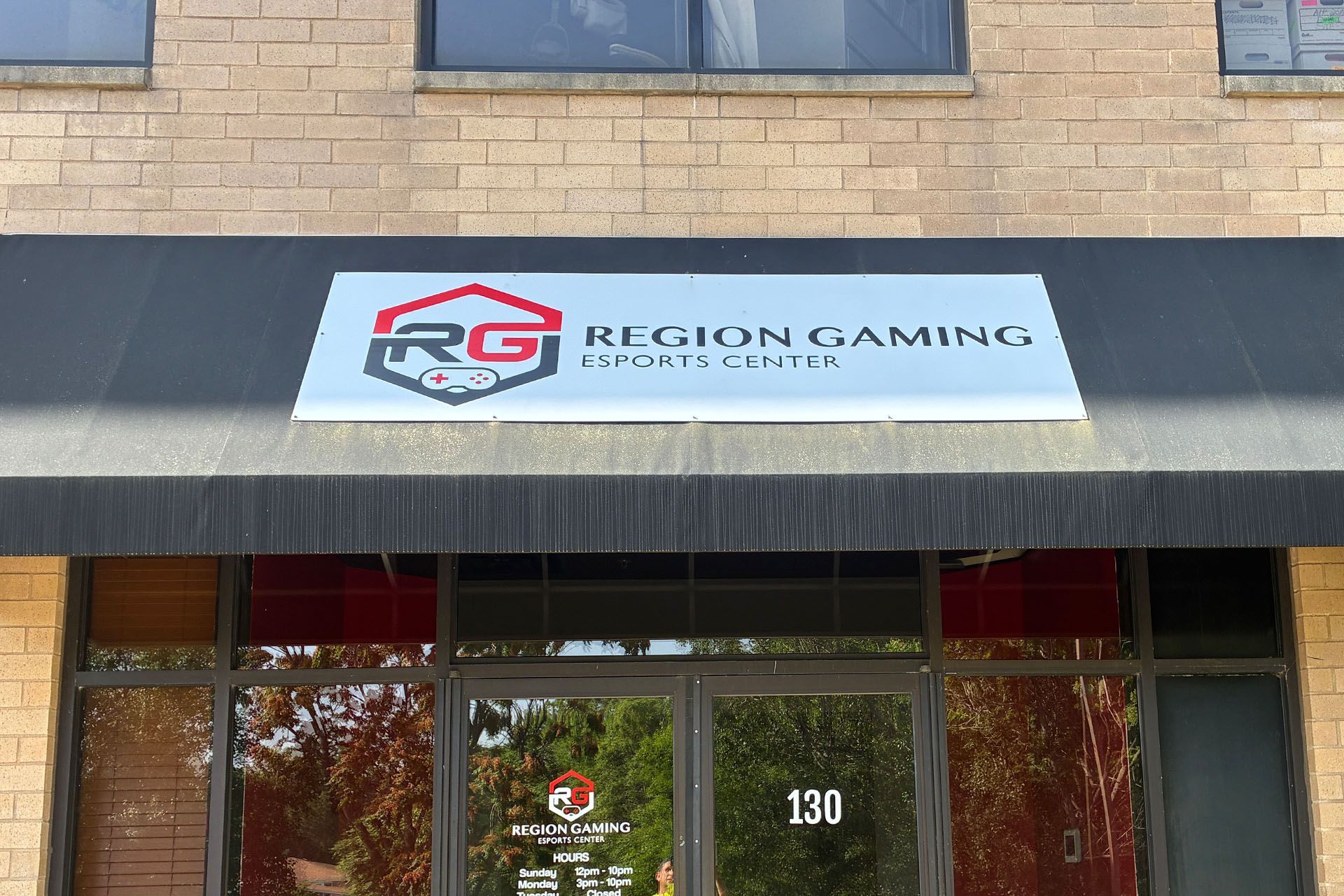 Sign for Region Gaming Lounge above a storefront entrance with glass doors and brick facade